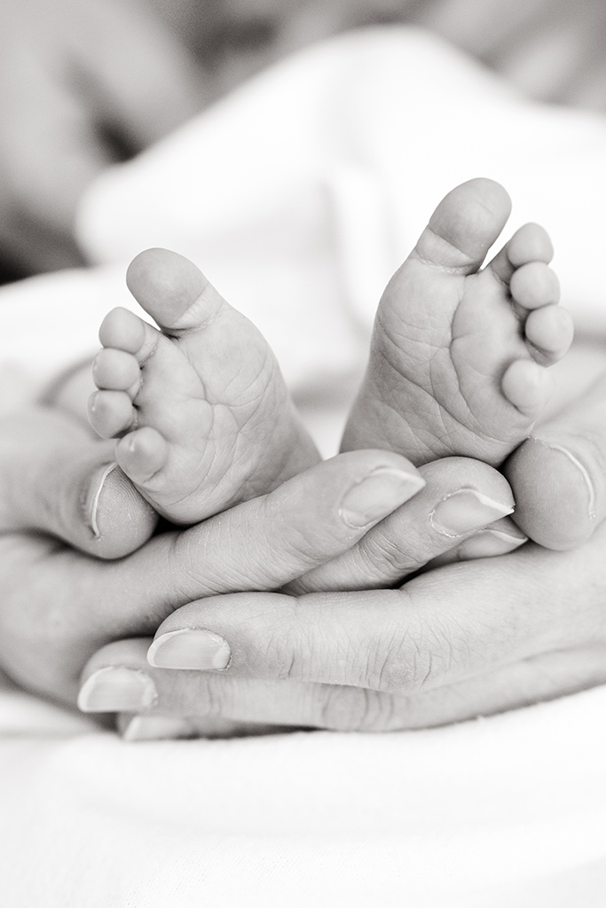 Füße eines Babys mit den Händen der Mutter. Baby Fotografie